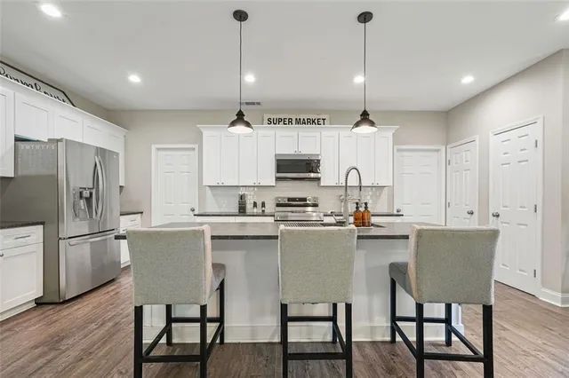 a kitchen with kitchen island a dining table chairs sink and cabinets