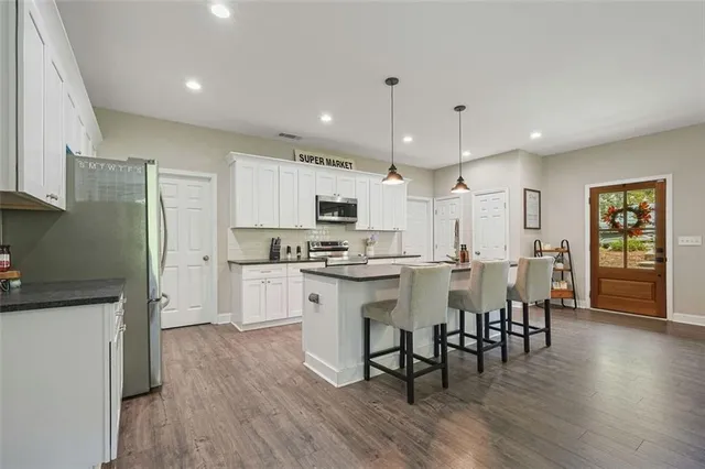 a kitchen with a dining table chairs wooden floor cabinets and stainless steel appliances