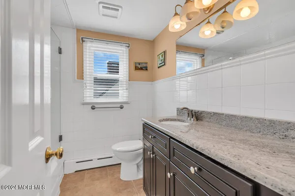 a bathroom with a granite countertop sink a toilet and mirror