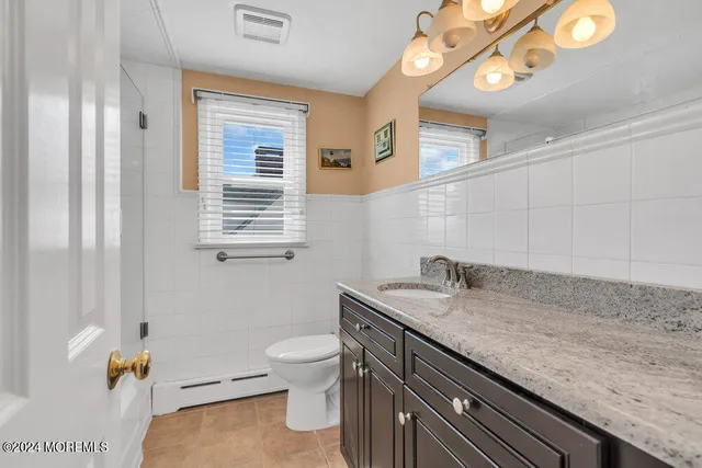 a bathroom with a granite countertop sink a toilet and mirror
