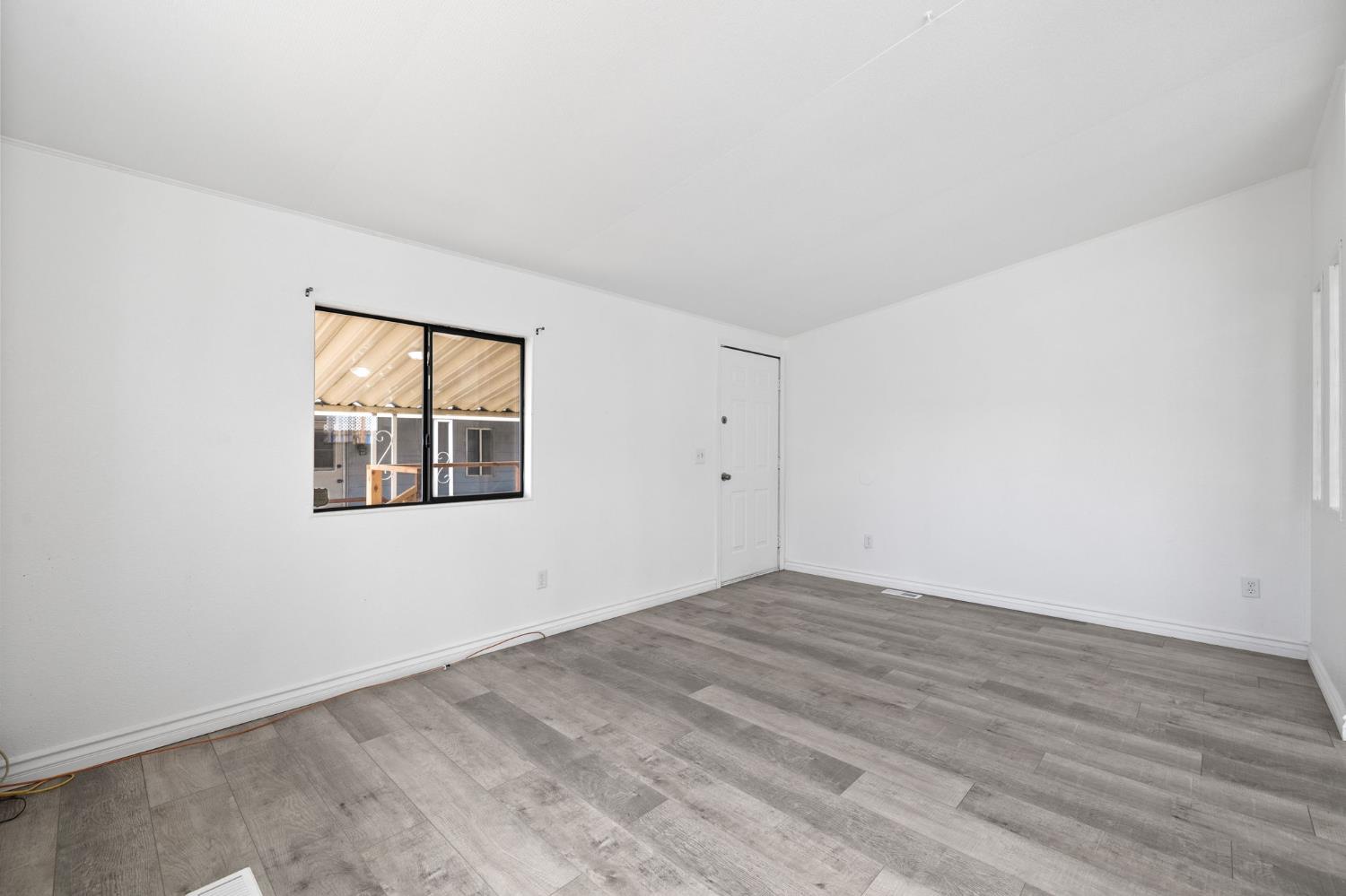 8300 Kern Canyon Road, Unit 156 Bakersfield, CA 93306 - Photo 8 of 40 an empty room with wooden floor and windows