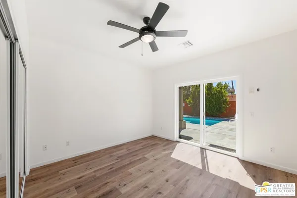 an empty room with wooden floor and windows
