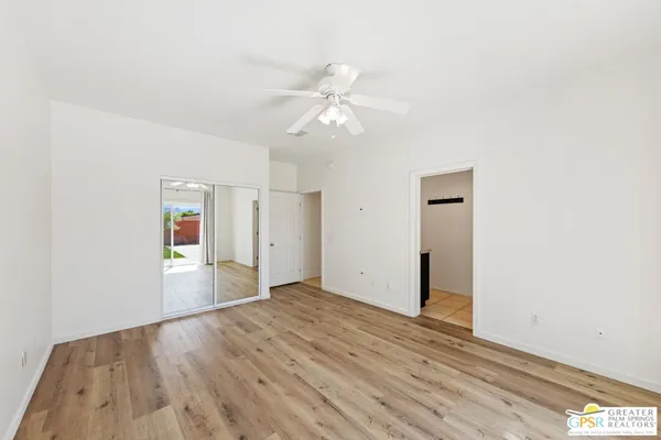an empty room with wooden floor ceiling fan and window