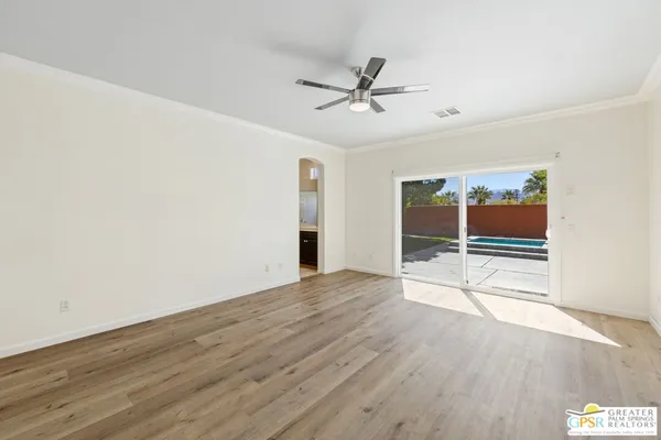a view of an empty room with wooden floor and a window