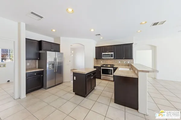 a kitchen with stainless steel appliances kitchen island granite countertop a refrigerator and a stove top oven