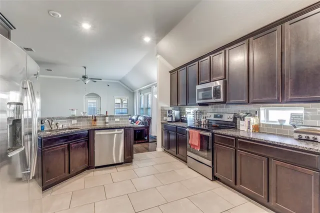 a open kitchen with stainless steel appliances granite countertop stove top oven microwave and cabinets