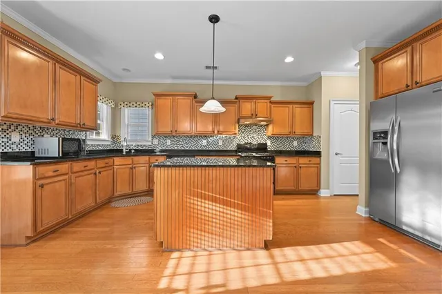a kitchen with stainless steel appliances granite countertop a stove a sink and a refrigerator