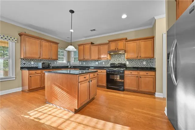 a kitchen with stainless steel appliances granite countertop a stove a sink and a refrigerator