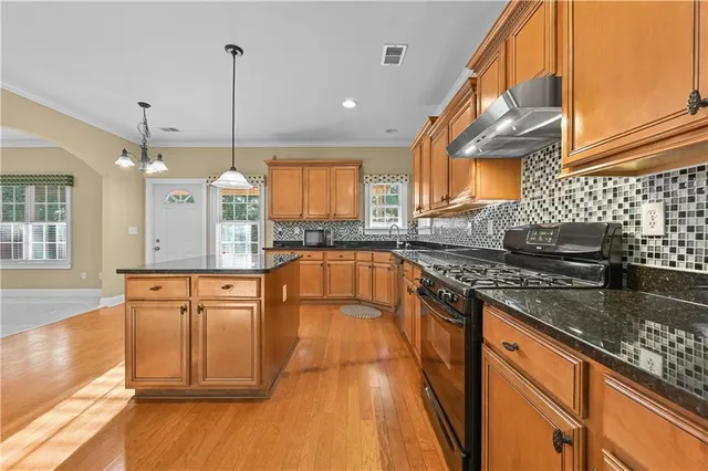 a large kitchen with stainless steel appliances granite countertop a stove a sink and a wooden cabinets