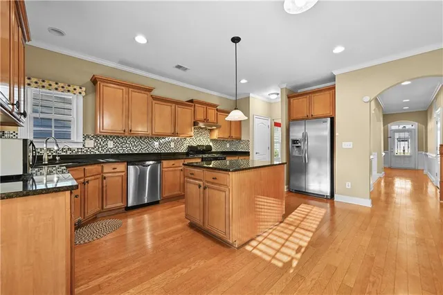 a kitchen with stainless steel appliances granite countertop a refrigerator a sink dishwasher a stove and white countertops with wooden floor