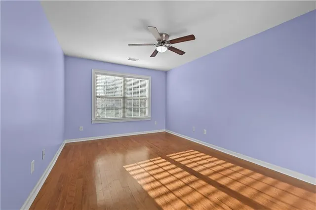 a view of an empty room with window and wooden floor