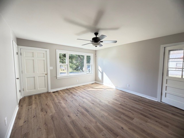 128 Stewart Street Cowan, TN 37318 - Photo 5 of 14 an empty room with wooden floor chandelier fan and windows