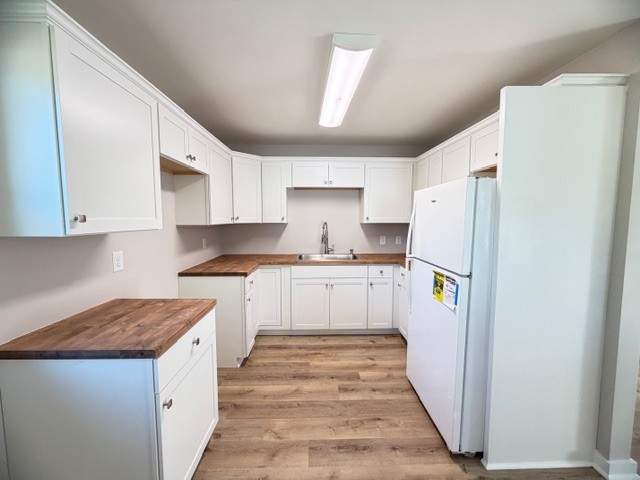 128 Stewart Street Cowan, TN 37318 - Photo 6 of 14 a kitchen with a refrigerator a stove and white cabinets