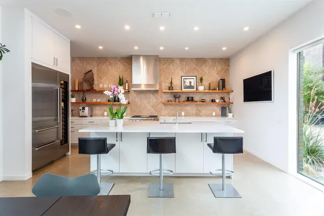 a kitchen with stainless steel appliances granite countertop a refrigerator a sink a stove a dining table and chairs