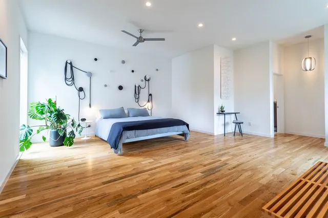 a spacious bedroom with a bed and a potted plant on table