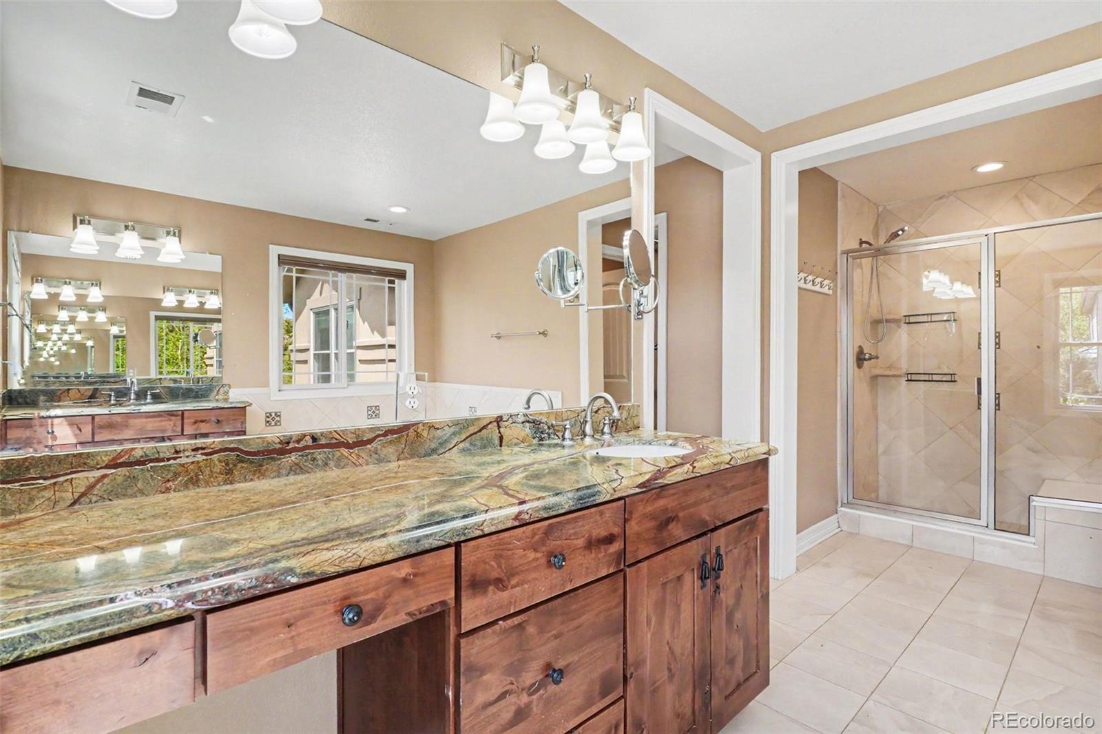 791 Elk Rest Road Evergreen, CO 80439 - Photo 23 of 46 a bathroom with a granite countertop sink mirror and a bath tub
