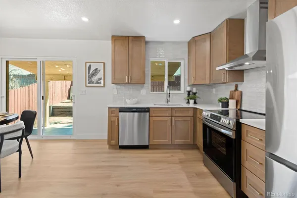 a kitchen with stainless steel appliances granite countertop wooden cabinets a sink a stove a refrigerator and island with wooden floor