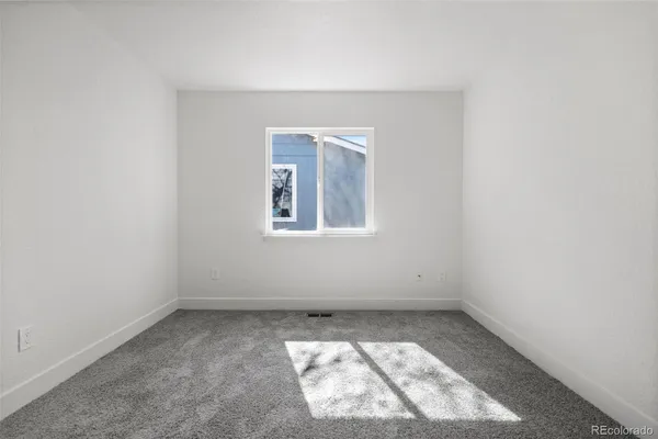 an empty room with a white cabinet and a window