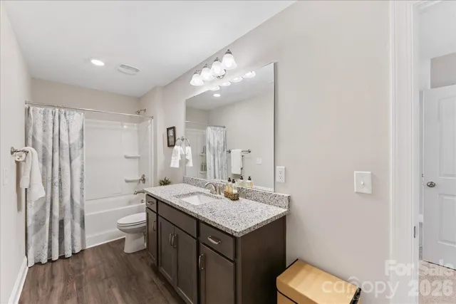a bathroom with a granite countertop sink a toilet a mirror and shower