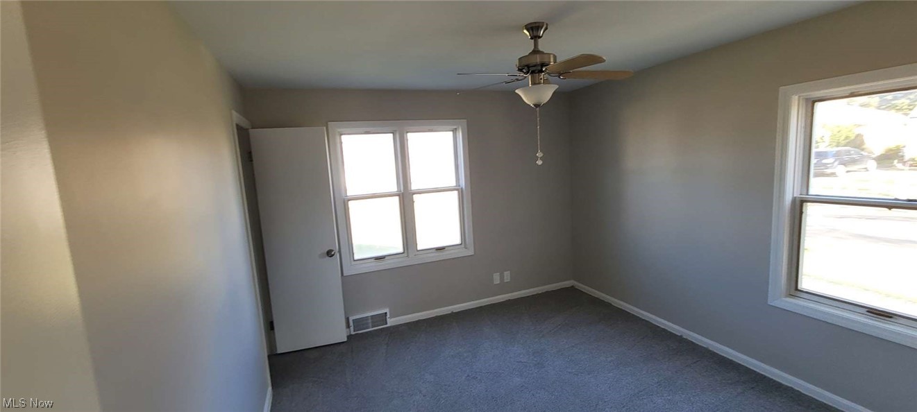 6149 North Canterbury Road Parma, OH 44129 - Photo 7 of 16 Empty room featuring dark colored carpet, ceiling fan, and a wealth of natural light