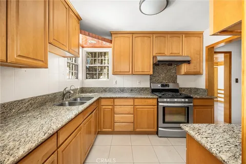 a kitchen with granite countertop a sink stove and cabinets