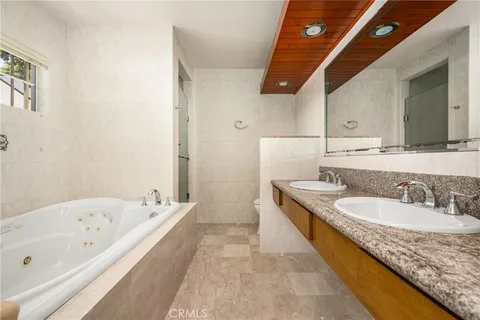 a bathroom with a granite countertop tub sink and mirror