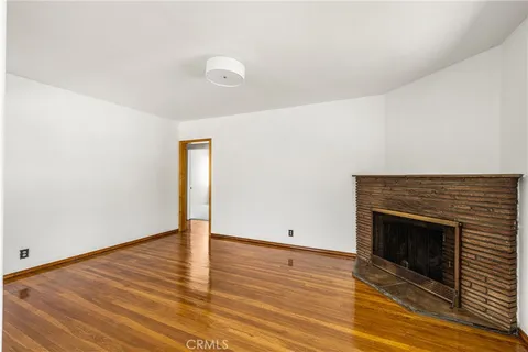a view of empty room with wooden floor and fireplace