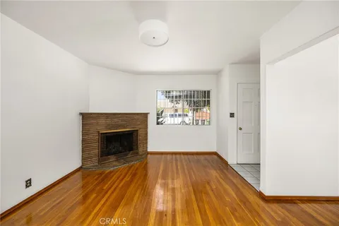 a view of empty room with wooden floor and fireplace
