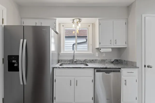 a kitchen with stainless steel appliances granite countertop a refrigerator and white cabinets