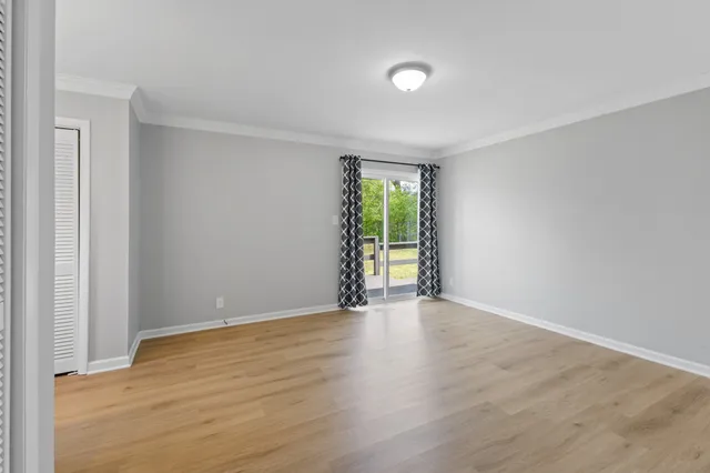 a view of an empty room with wooden floor and a window