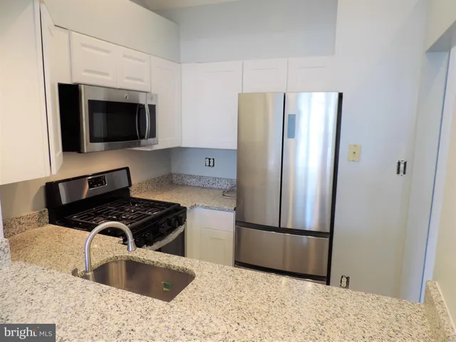 a kitchen with stainless steel appliances granite countertop a refrigerator a stove and a sink