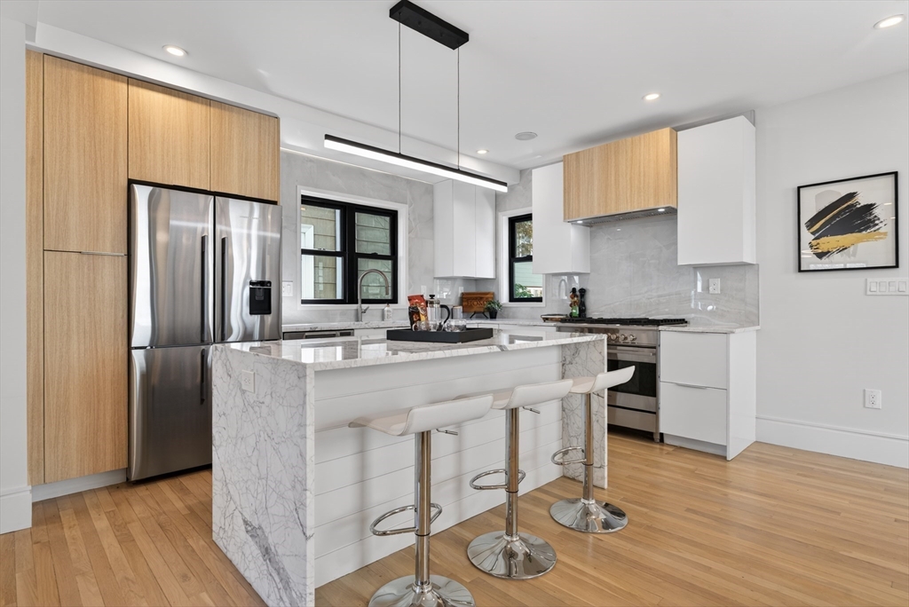 29 Line Street Cambridge, MA 02138 - Photo 10 of 42 a kitchen with stainless steel appliances granite countertop a refrigerator a stove top oven a sink dishwasher and white cabinets with wooden floor