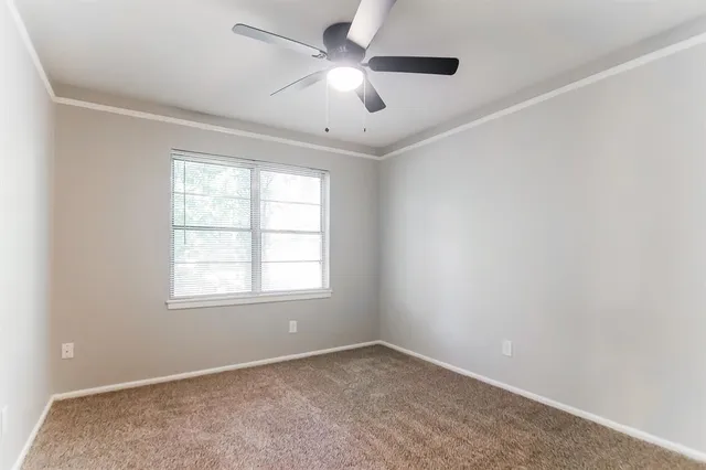 an empty room with a window and a fan