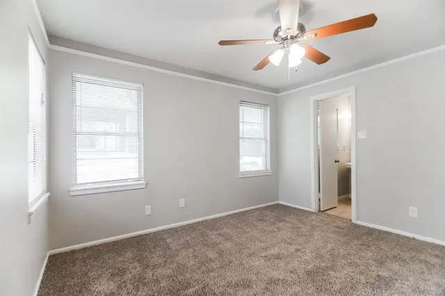 a view of an empty room with window and chandelier fan