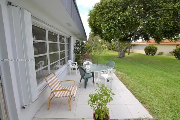 a view of a chairs and table in the patio next to a yard