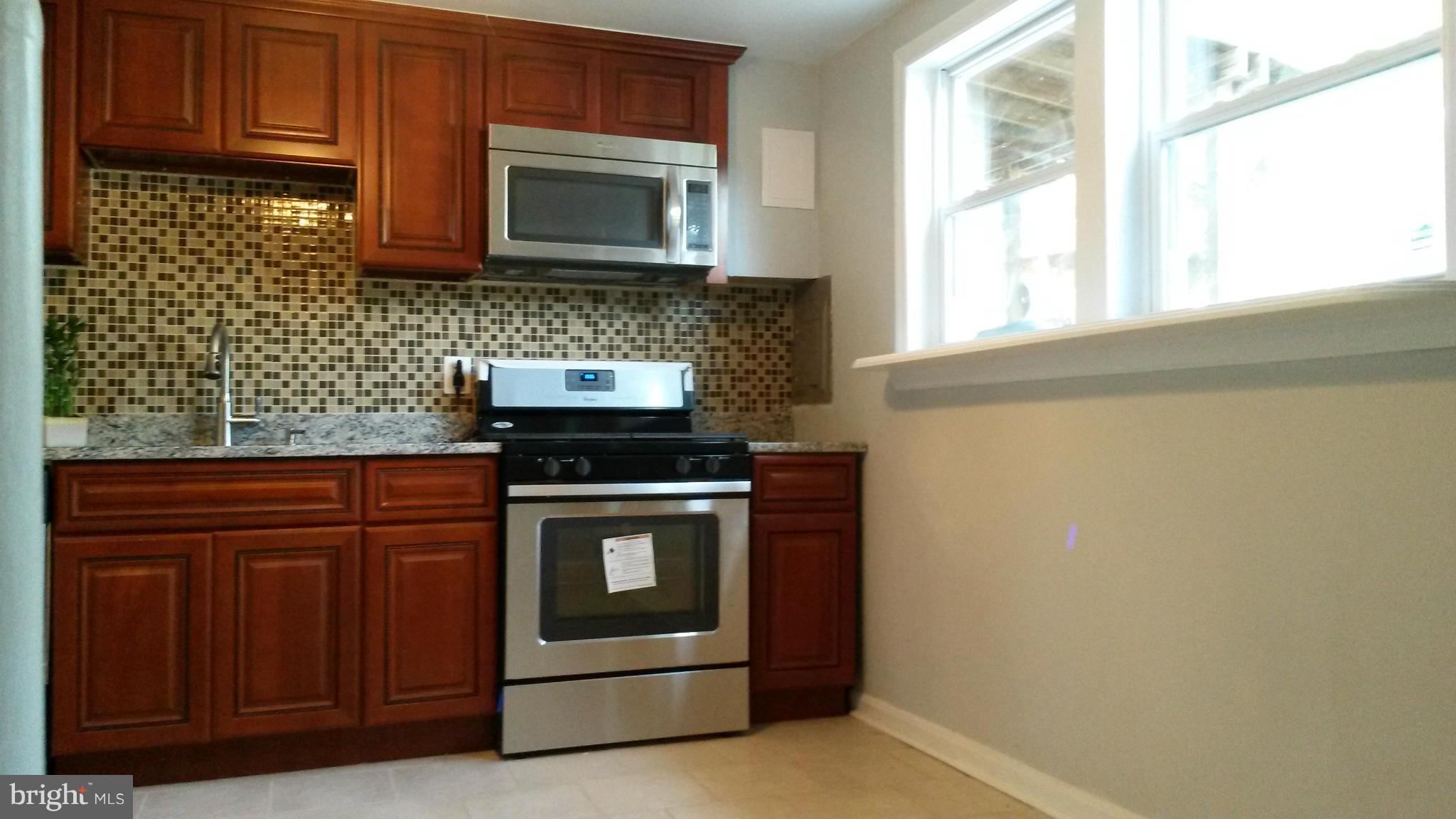 3304 Bero Road Baltimore, MD 21227 - Photo 4 of 27 a kitchen with stainless steel appliances granite countertop a stove microwave and cabinets