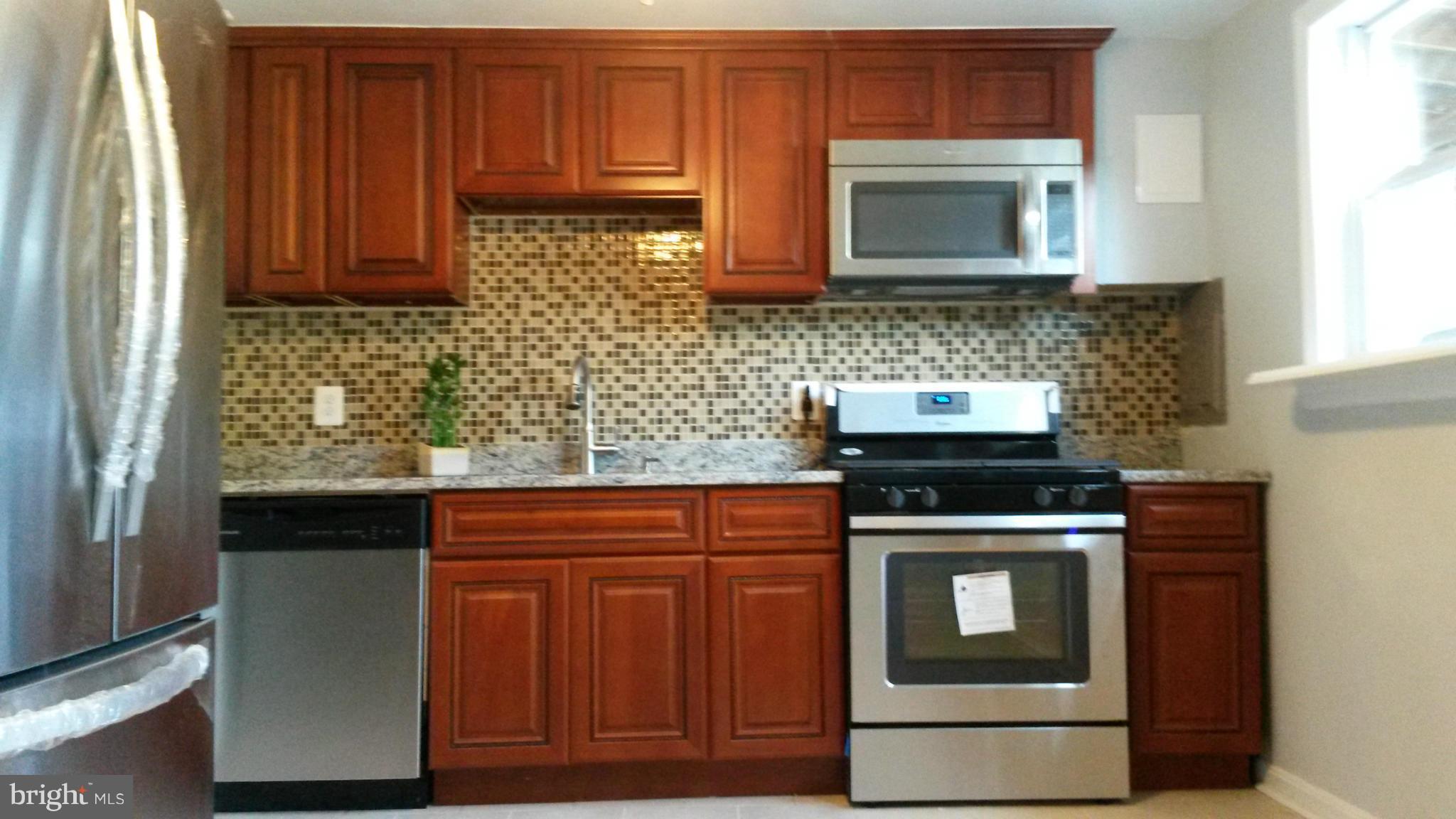 3304 Bero Road Baltimore, MD 21227 - Photo 7 of 27 a kitchen with stainless steel appliances granite countertop a stove microwave and cabinets
