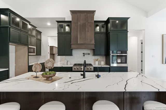 a kitchen with stainless steel appliances kitchen island granite countertop a table chairs in it and wooden floors