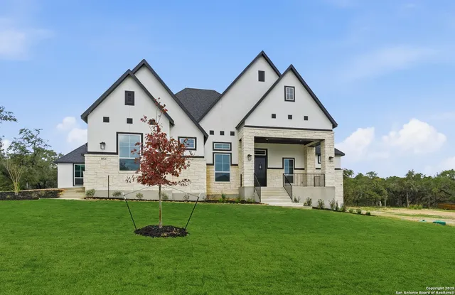 a view of a house with a big yard plants and large trees