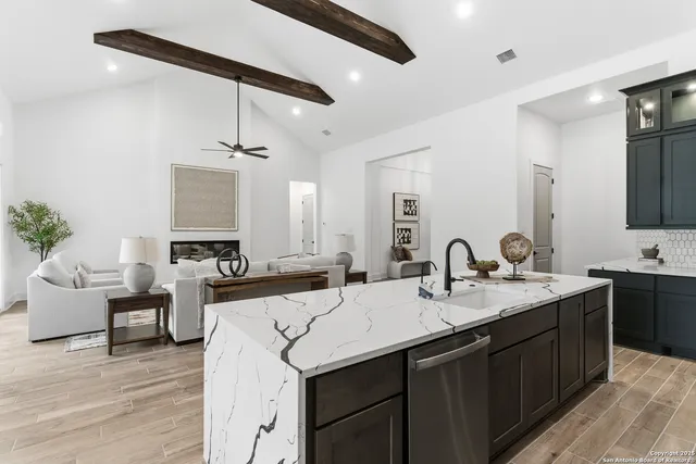 a kitchen with a sink dishwasher a stove a dining table and chairs with wooden floor