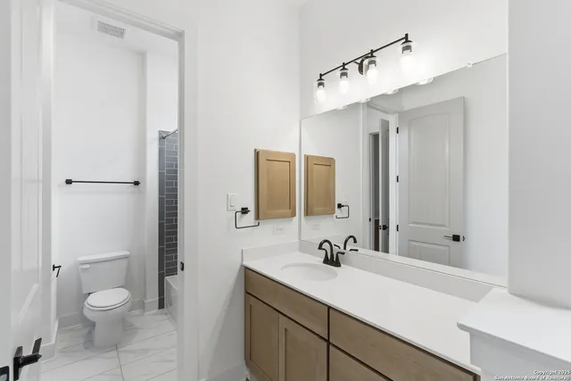 a view of an empty room with kitchen and window