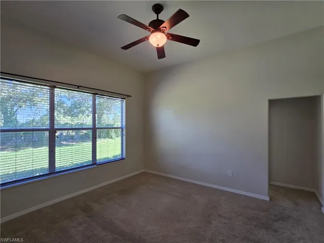 an empty room with a window and a fan