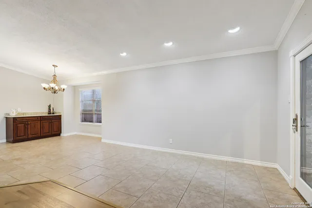 an empty room with kitchen and chandelier