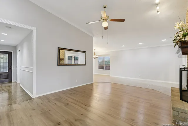 an empty room with wooden floor and ceiling fan