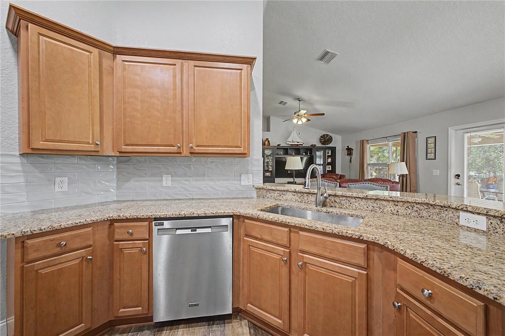 11213 Flock Avenue Weeki Wachee, FL 34613 - Photo 8 of 46 a kitchen with stainless steel appliances granite countertop a sink and cabinets with wooden floor