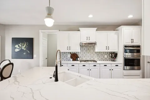 a kitchen with white cabinets and sink
