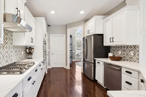 a kitchen with stainless steel appliances white cabinets and wooden floor