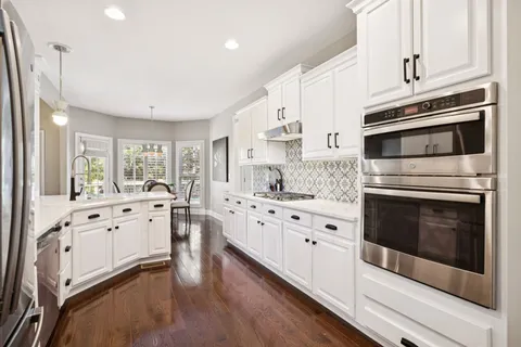 a kitchen with stainless steel appliances white cabinets and wooden floors