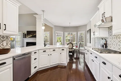 a large white kitchen with stainless steel appliances granite countertop a lot of counter space and wooden floors