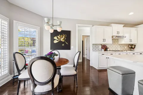 a kitchen with stainless steel appliances granite countertop a dining table chairs refrigerator and sink